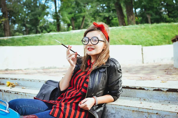 Молода хіпстерка в окулярах сидить на сходах і курить сигарету — стокове фото