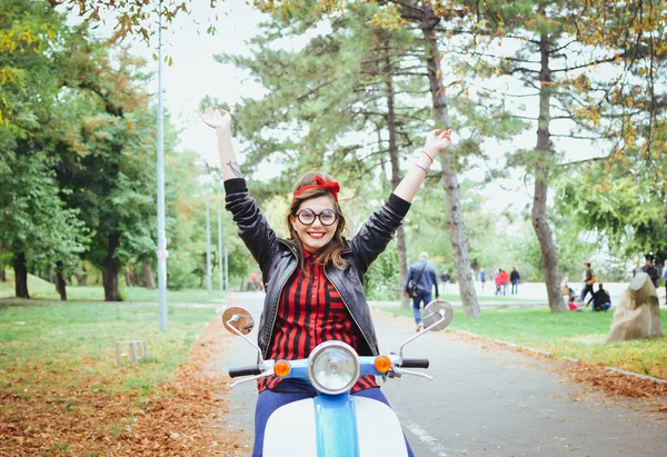 Feliz jovem hipster mulher em óculos se divertindo em scooter vintage no parque — Fotografia de Stock