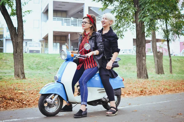 Duas jovens mulheres se divertindo com scooter vintage no parque — Fotografia de Stock