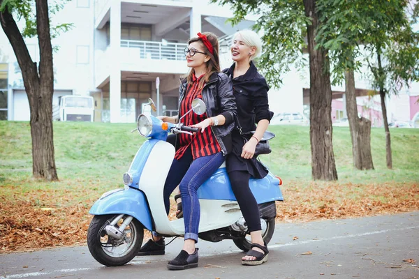 İki genç kadın parkta vintage scooter ile biraz eğlenmek