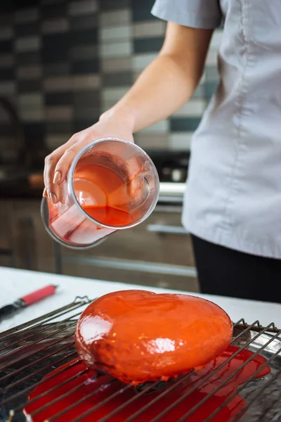 Процесс выливания глазури на торт в виде сердца — стоковое фото