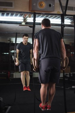 Spor süspansiyon halkaları üzerinde yapan genç ve güzel erkek çeker