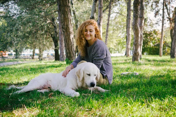 Junge Frau sitzt mit Hund im Park — Stockfoto