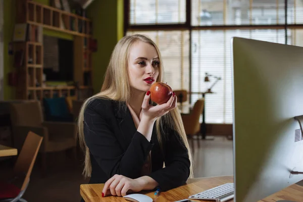 Женщина ест яблоко в офисе — стоковое фото