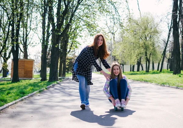 Positive Schwestermädchen laufen, skateboarden und haben gemeinsam Spaß im Park — Stockfoto