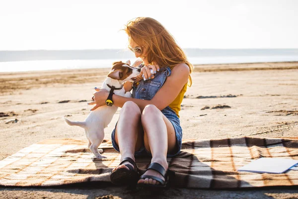 Молодая стильная хипстерша играет в собачку Джека Рассела на пляже — стоковое фото