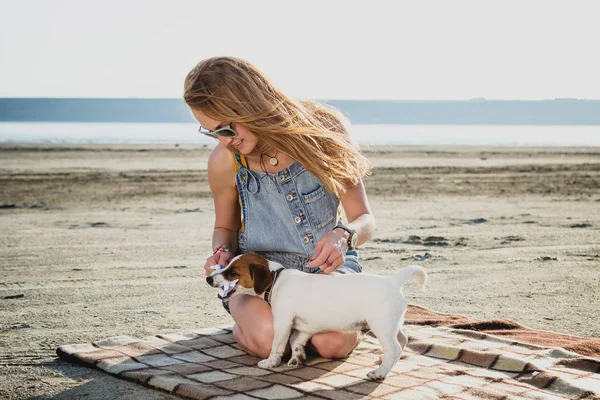 Jovem elegante hipster menina jogando cachorro cão jack russell na praia — Fotografia de Stock
