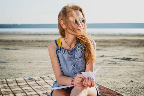 Gadis hipster bergaya muda dengan origami di pantai — Stok Foto