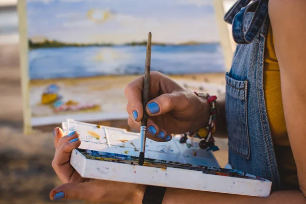 Young woman artist painting landscape in the open air on the beach, close up — Stock Photo, Image