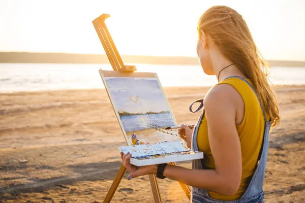 Young woman artist painting landscape in the open air on the beach — Stock Photo, Image