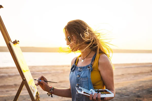 Junge Künstlerin bemalt Landschaft unter freiem Himmel am Strand — Stockfoto