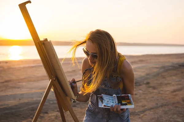 Junge Künstlerin bemalt Landschaft unter freiem Himmel am Strand — Stockfoto