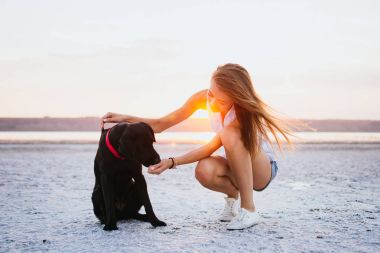 Genç erkek ile labrador retriever köpek sahilde günbatımı sarılma