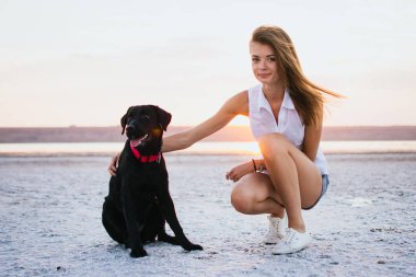 Genç erkek ile labrador retriever köpek sahilde günbatımı sarılma