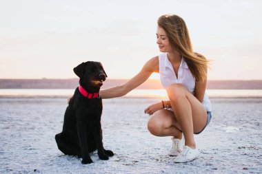 Genç erkek ile labrador retriever köpek sahilde günbatımı sarılma