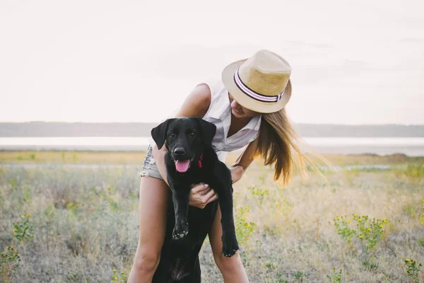 Jovem fêmea com cão labrador retriever no campo ao pôr do sol — Fotografia de Stock