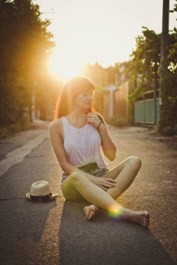 Kırsal kesimde yolda oturan şapkalı genç kadın