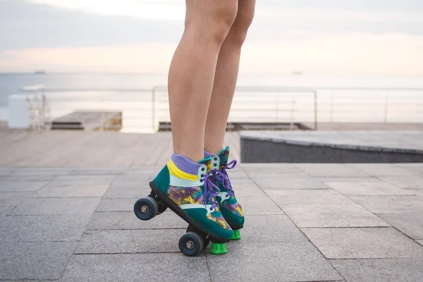 Young woman roller skating near the sea on roller squads, close up