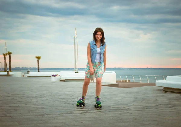 Mulher jovem patinagem perto do mar em esquadrões de rolos — Fotografia de Stock