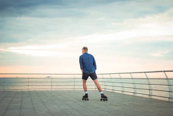 Young caucasian man roller skating with quad skates near the sea