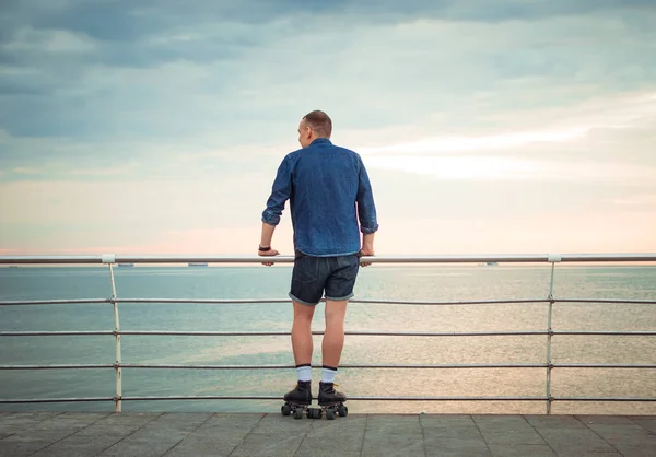 Young caucasian man roller skating with quad skates near the sea