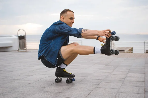 Joven hombre caucásico patinaje sobre ruedas con patines quad cerca del mar — Foto de Stock