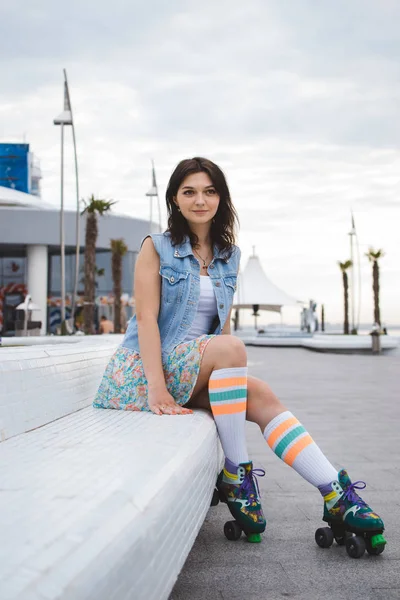 Portrait of young woman roller skating near the sea on roller squads