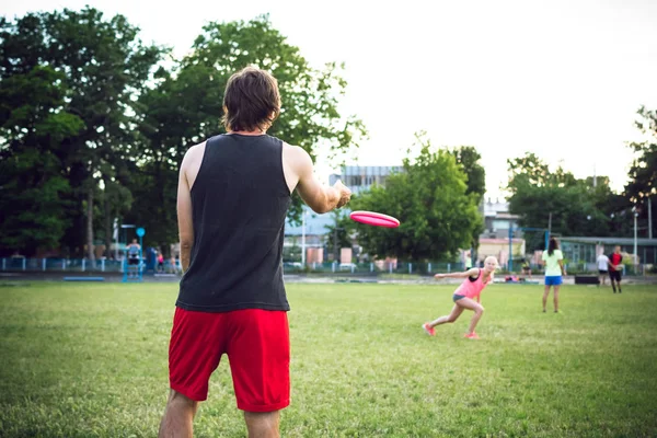 Jonge man en vrouw frisbee in het park spelen tijdens zonsondergang — Stockfoto