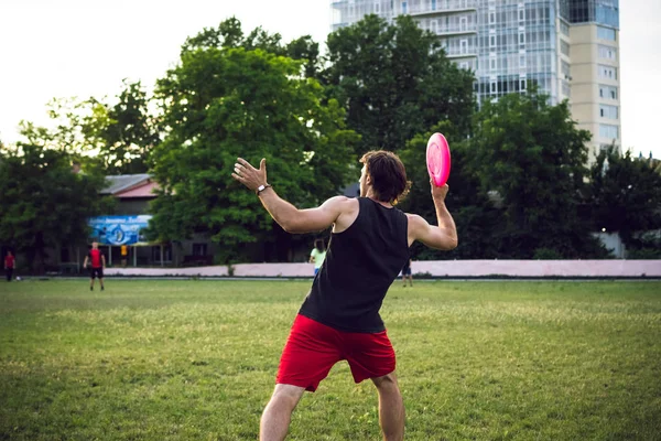 Joven jugando frisbee en el parque al atardecer —  Fotos de Stock