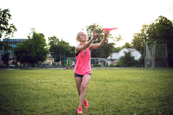 Jovem e bela mulher jogando frisbee no parque — Fotografia de Stock