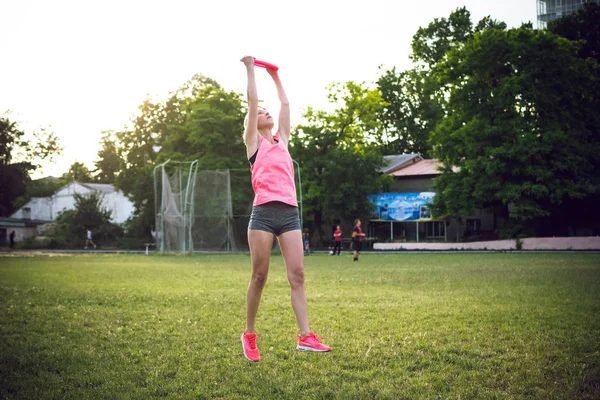 Jovem e bela mulher jogando frisbee no parque — Fotografia de Stock