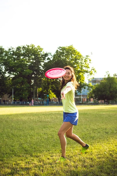 Mujer joven y hermosa jugando frisbee en el parque — Foto de Stock