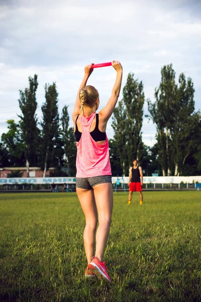 Jonge vrouw en man frisbee in het park spelen tijdens zonsondergang — Stockfoto