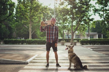 Sokak yol üzerinde kaykay ve Sibirya husky köpek duran adamla genç yenilikçi