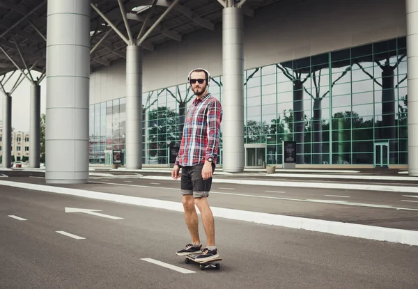 Joven hipster hombre paseos en el monopatín en la calle carretera — Foto de Stock