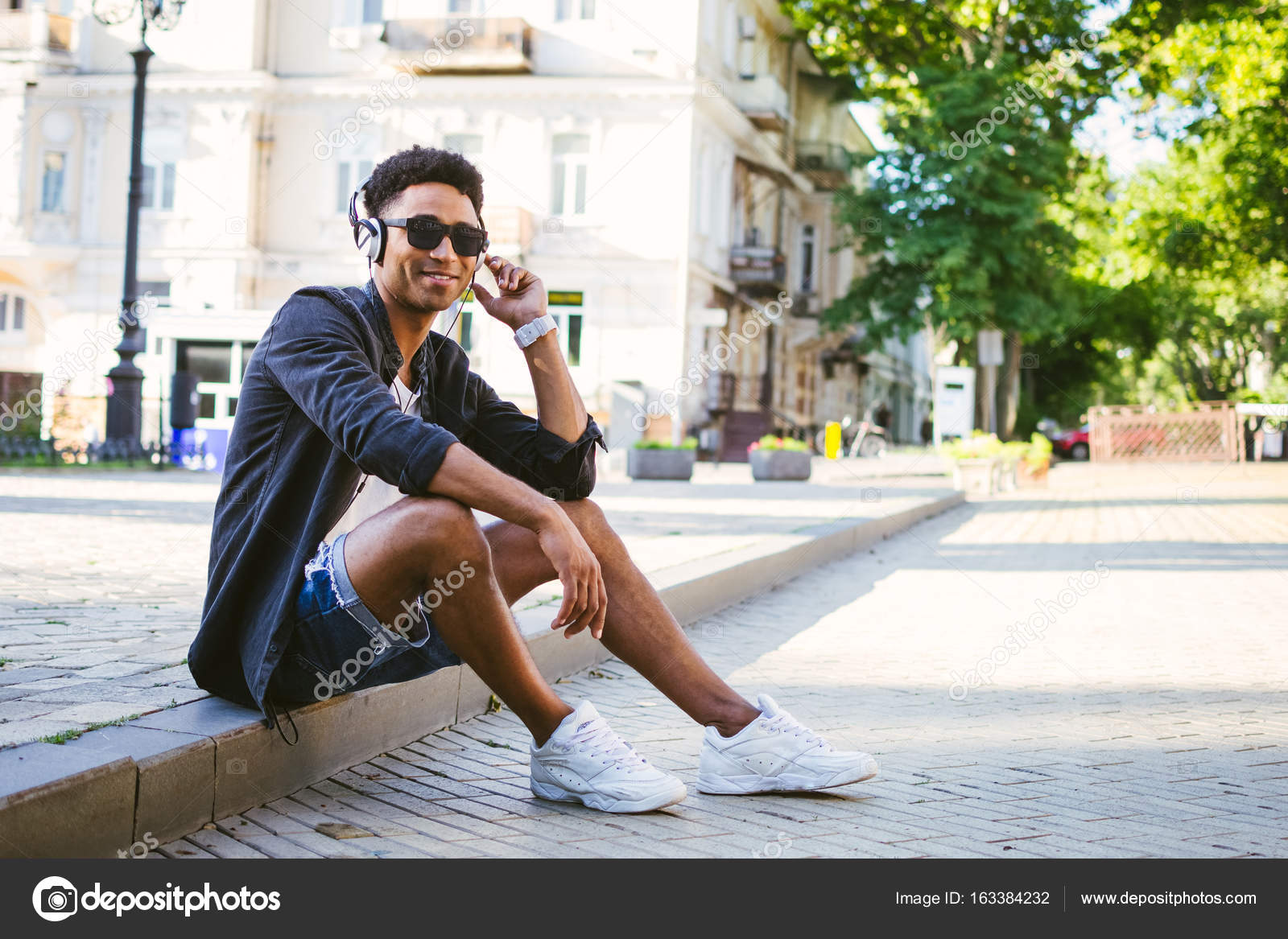 Portrait of young stylish hipster black man in white headphones and sun ...