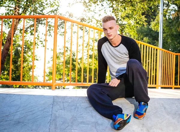 Jovem homem parkour sentado no parque de skate na cidade — Fotografia de Stock