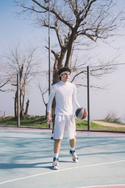 Bir açık basketbol sahası üzerinde yürüme ve top top sürme bir basketbol oyuncusu portresi