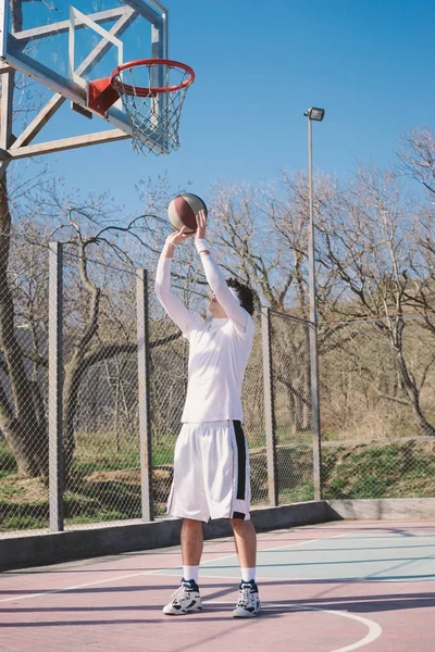 Porträt eines Basketballspielers, der auf einem Outdoor-Basketballfeld geht und den Ball dribbelt — Stockfoto