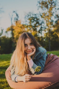 Renkli lolipop, açık çanta koltuğa oturan genç hipster kadın