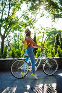 Genç güzel kadın yaz Park'taki bisiklet sürme. Yeşil ağaçlar arka plan 