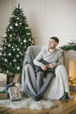 Noel ağaçları ve şömine, kapalı yakınında oturan genç Avrupa adam