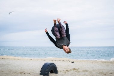 Denize sıfır plaj üzerinde Parkour hile yapan genç erkek