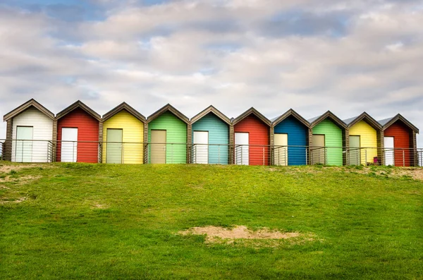 Fila di colorate capanne da spiaggia sotto il cielo nuvoloso — Foto Stock