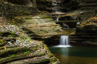 Derin bir geçit altındaki küçük şelale