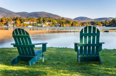 Yeşil Adirondack sandalyeler önünde bir dağ gölü Güz