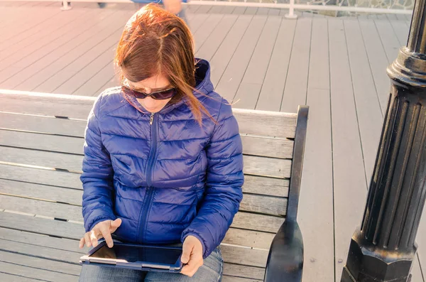 Mujer Tourist Consulting una tableta mientras está sentada al aire libre — Foto de Stock