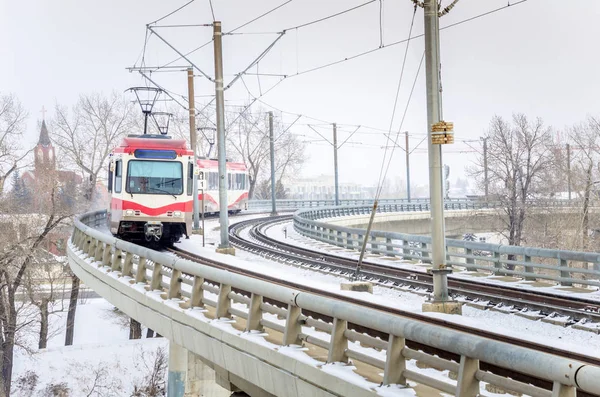 Kevyt juna kaartavalla sillalla lumisena päivänä — kuvapankkivalokuva