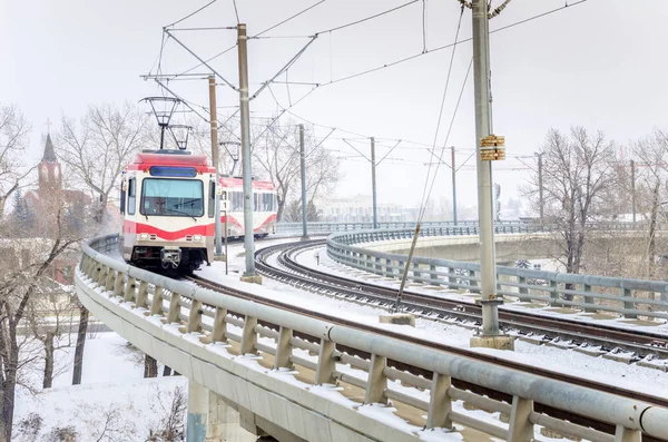 Treno leggero su un ponte in curva in una giornata innevata — Foto Stock