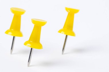 Üç sarı Pushpins beyaz kağıt üzerinde